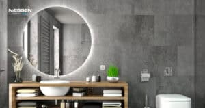 Baño moderno con mecanismos eléctricos Niessen Zenit integrados en pared de cemento, espejo redondo retroiluminado y mueble de madera