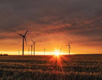Parque eólico al atardecer con aerogeneradores en un campo de cereales, simbolizando la transición energética y la sostenibilidad