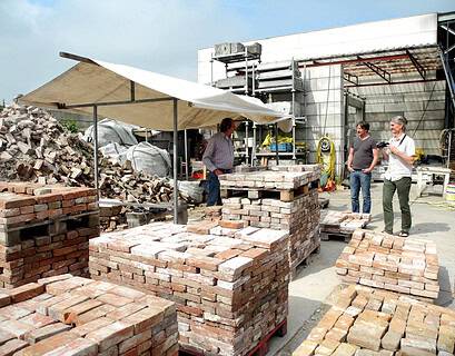 Trabajadores junto a palés de ladrillos reutilizados en una planta de reciclaje de materiales de construcción, ejemplo de ciclabilidad en la edificación